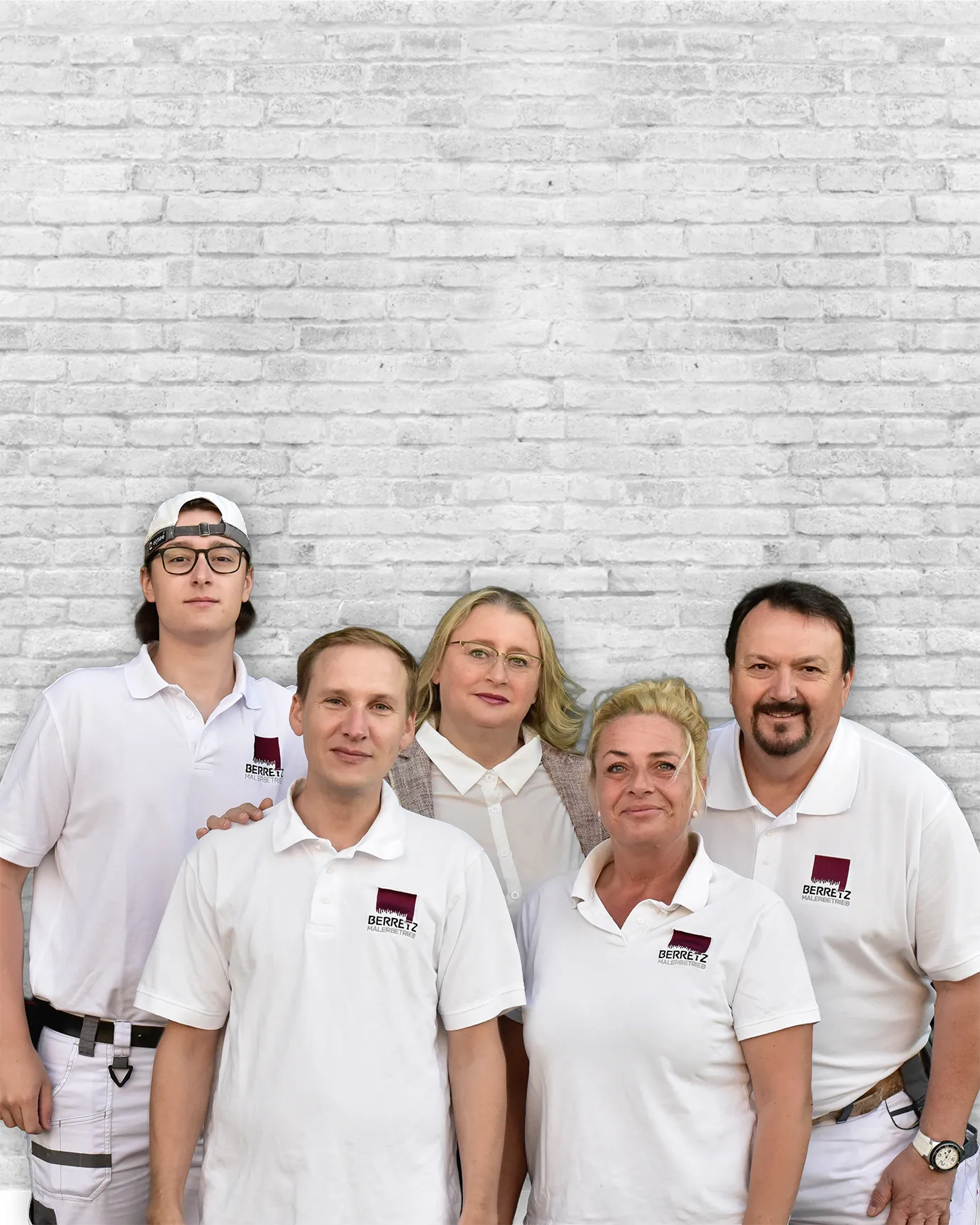 Fünf Personen in weißer Arbeitskleidung vor weißer Ziegelwand, Teamfoto mit drei Männern und zwei Frauen.